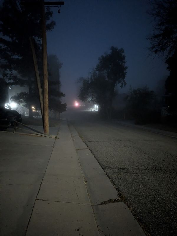 Street in heavy fog at blue hour with the lit APEX I Alpha Unit visible about 300 ft away