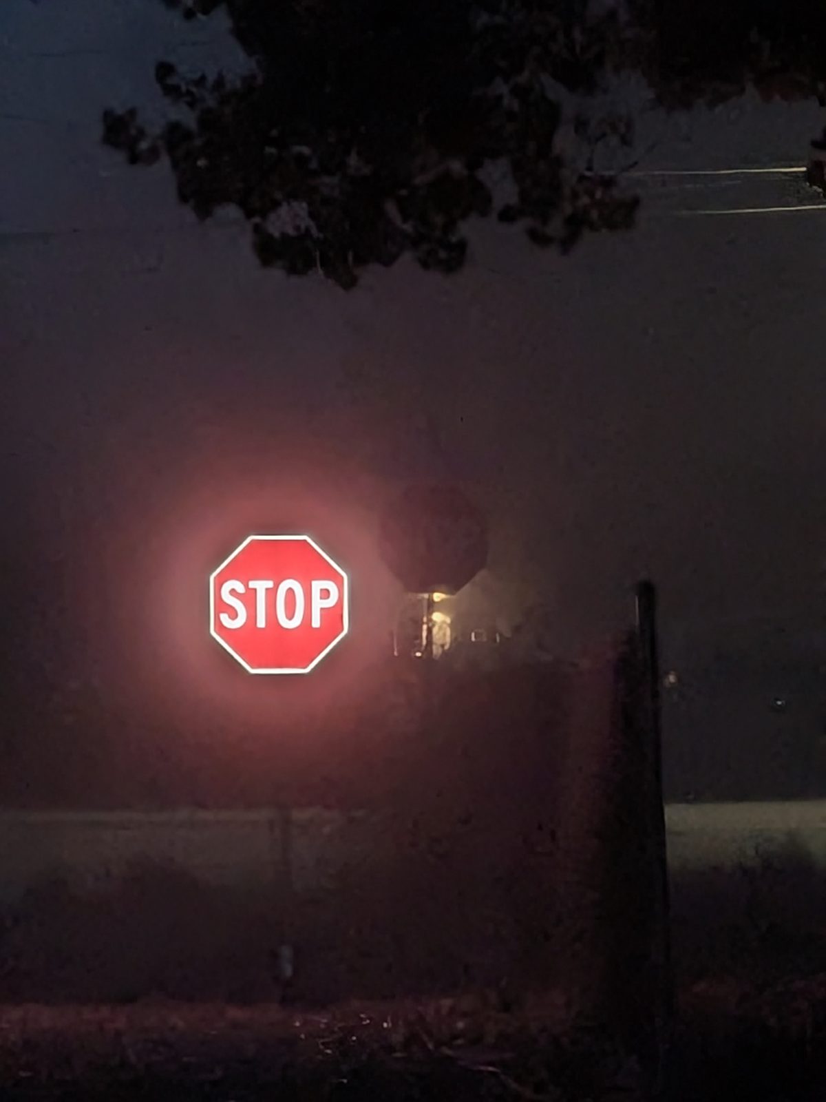 APEX I Alpha Unit STOP sign lit in heavy fog from about 100 ft, with a standard STOP sign behind it