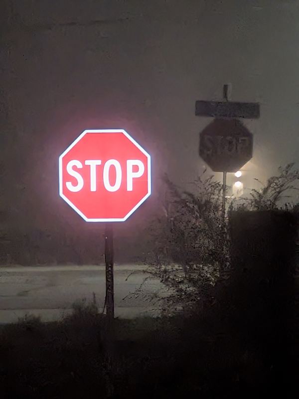 APEX I Alpha Unit R1-1 STOP sign, lit, in heavy fog with a standard STOP sign behind it
