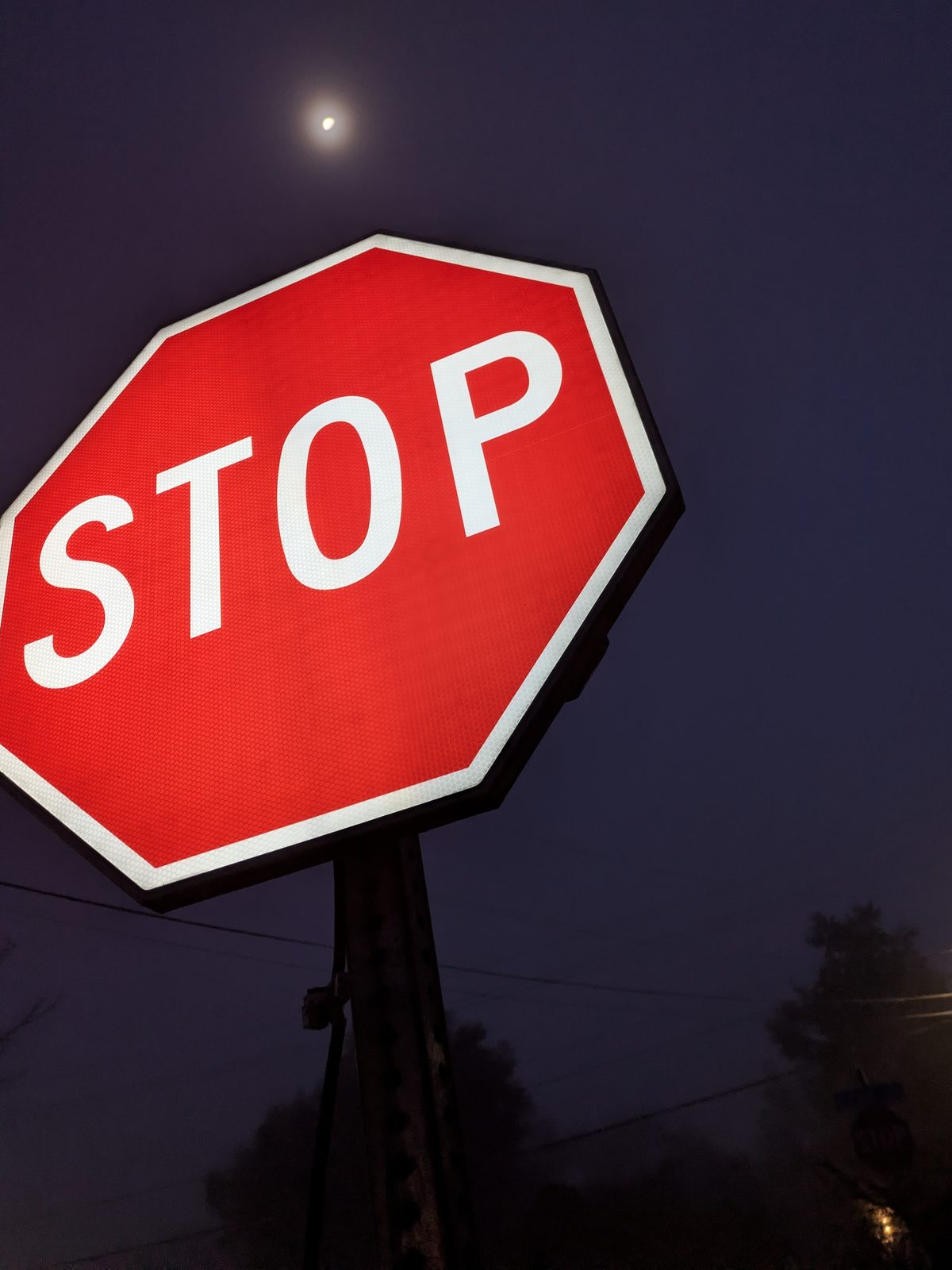 APEX I Alpha Unit STOP sign lit, seen from below with a streetlight in fog