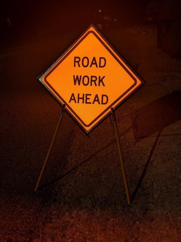 APEX I Alpha Unit W20-1 ROAD WORK AHEAD sign, lit at night on a portable stand